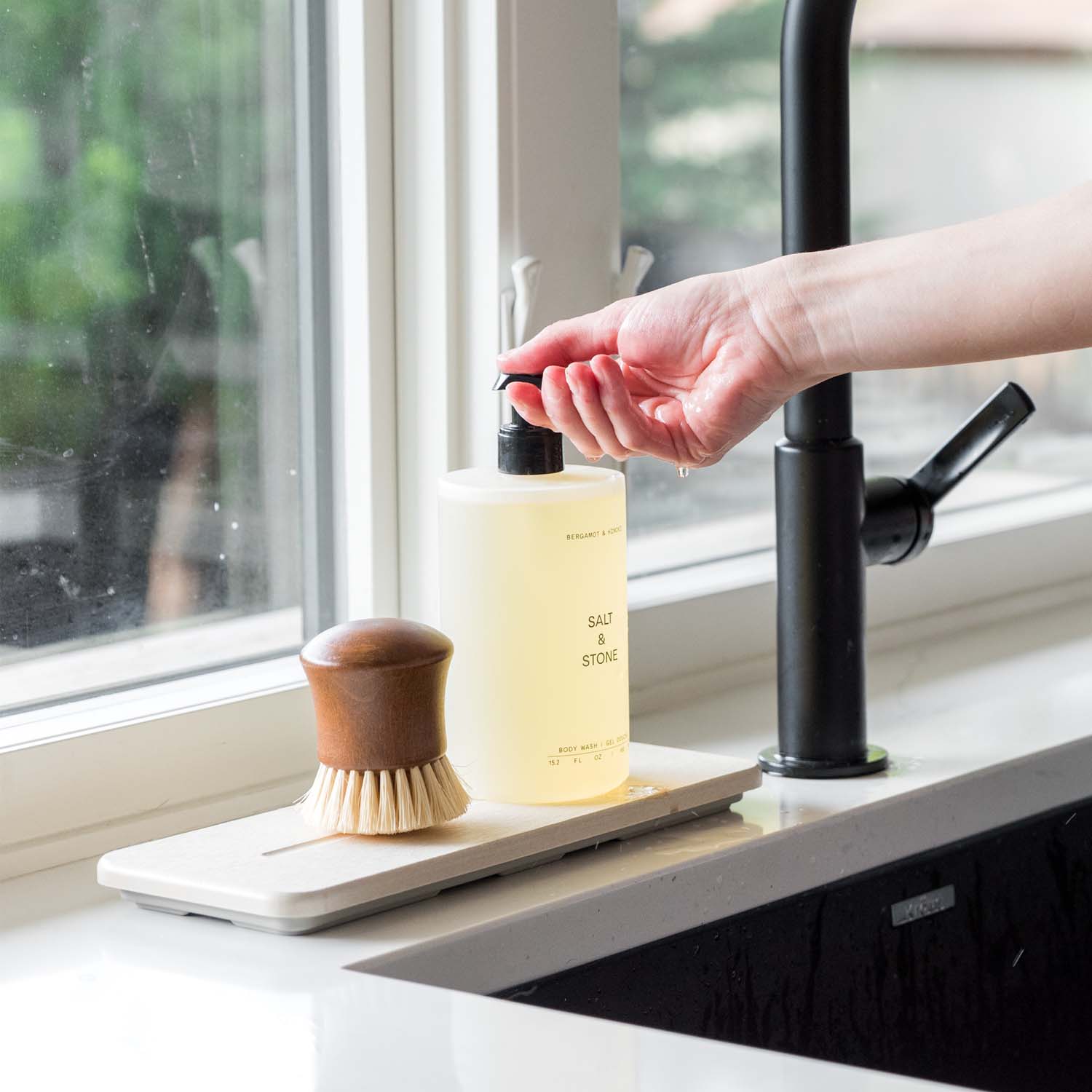 woman pumping soap from soap dispenser on top of sink caddy