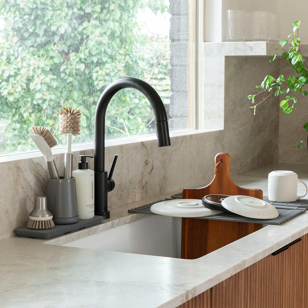 dished draining into sink on top of dish drainer with brush holder in dark grey