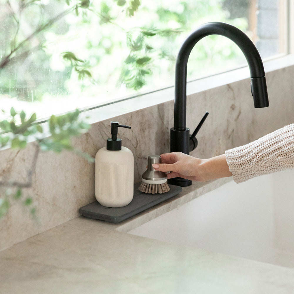 woman putting dish brush on top of sink organizer