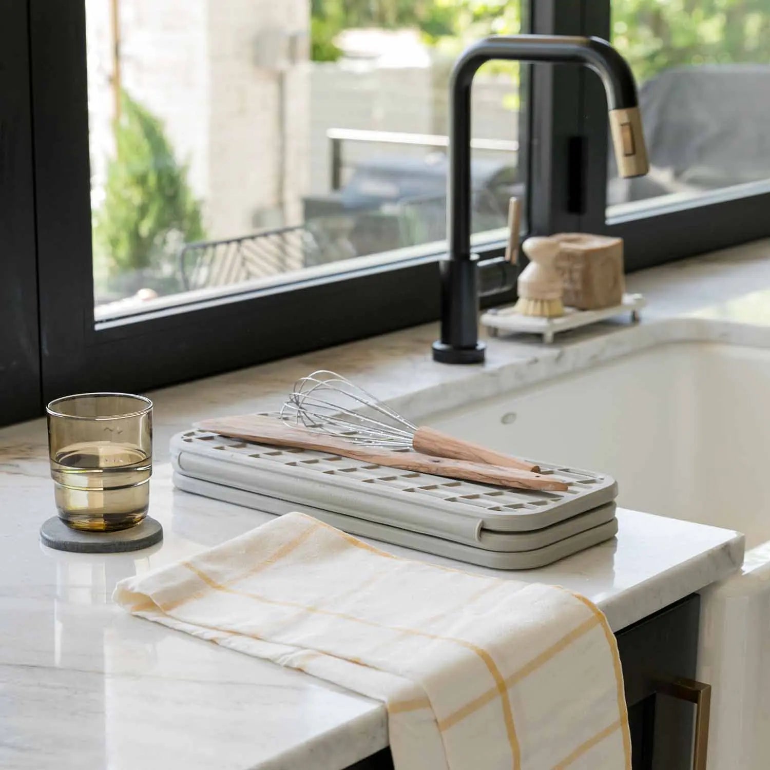 sandstone dish pad next to sink with utensils on it