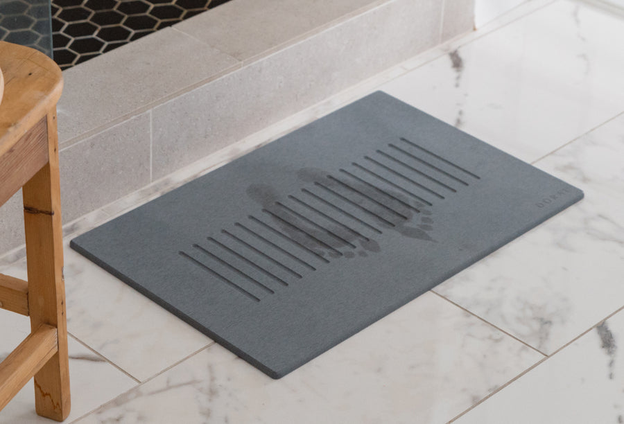 shower mat in front of shower with foot prints