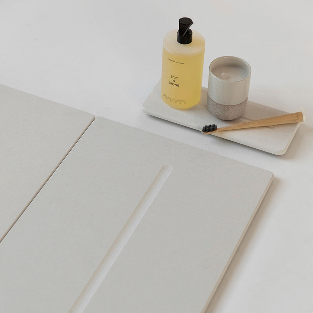 off white sink organizer with brush and candle with matching bathroom stone mat
