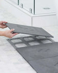 person putting slate large bath stone mat panel onto last panel spot