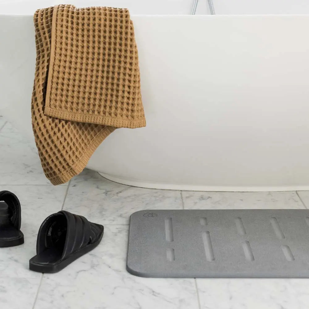 Bath Stone Mat Rain Slate next to bath tub and shoes and towel
