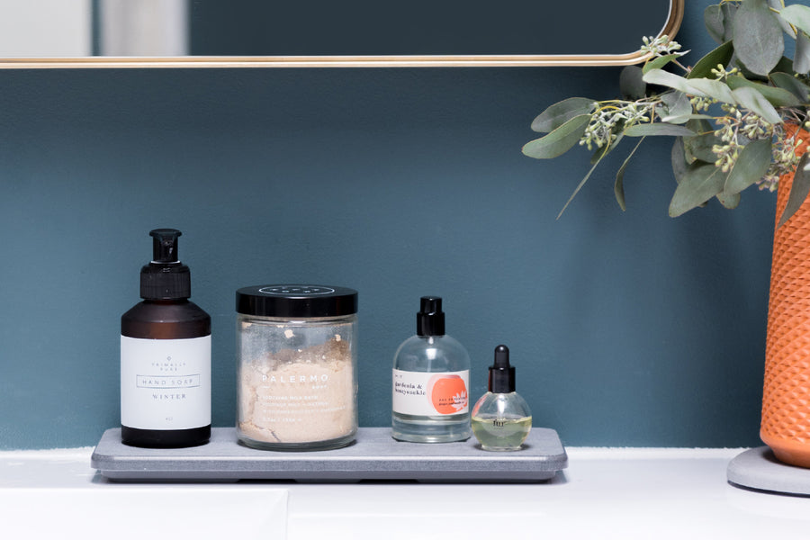 Dorai Stone Sink Caddy in Slate color, organized with bathroom accessories on a countertop.