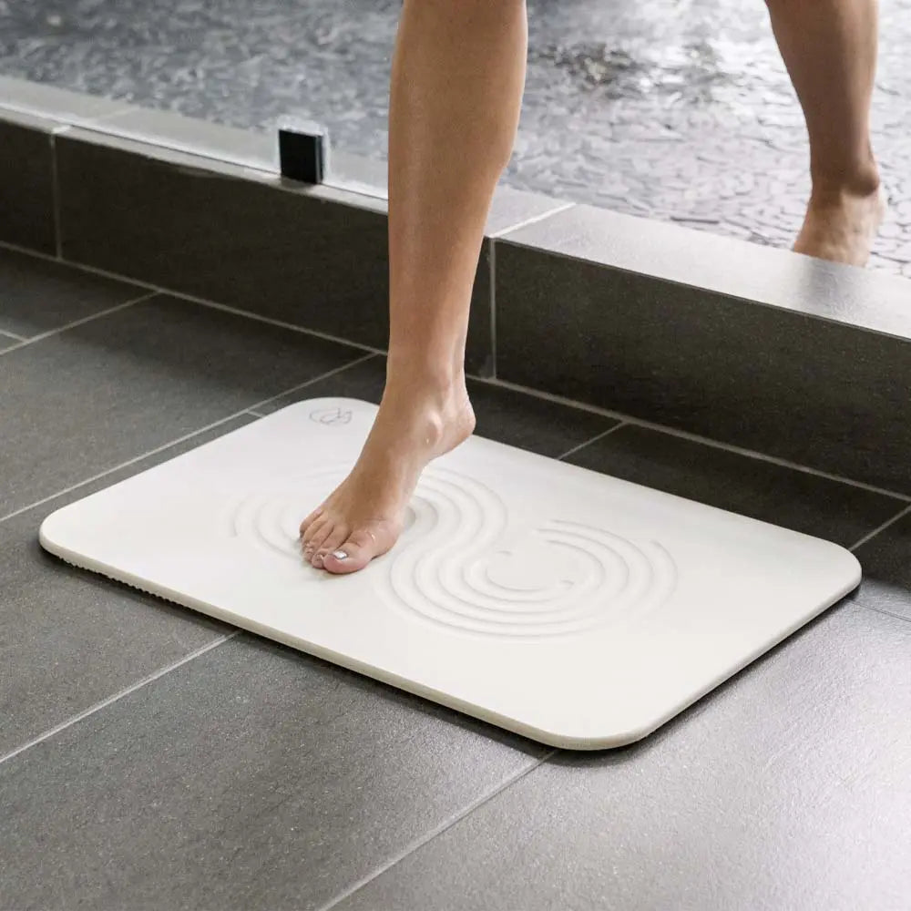 Woman stepping out of shower onto sandstone zen bath stone mat 