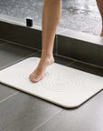 Woman stepping out of shower onto sandstone zen bath stone mat 