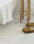 Sandstone Zen Bath Stone Mat with shoes and stool next to bath tub