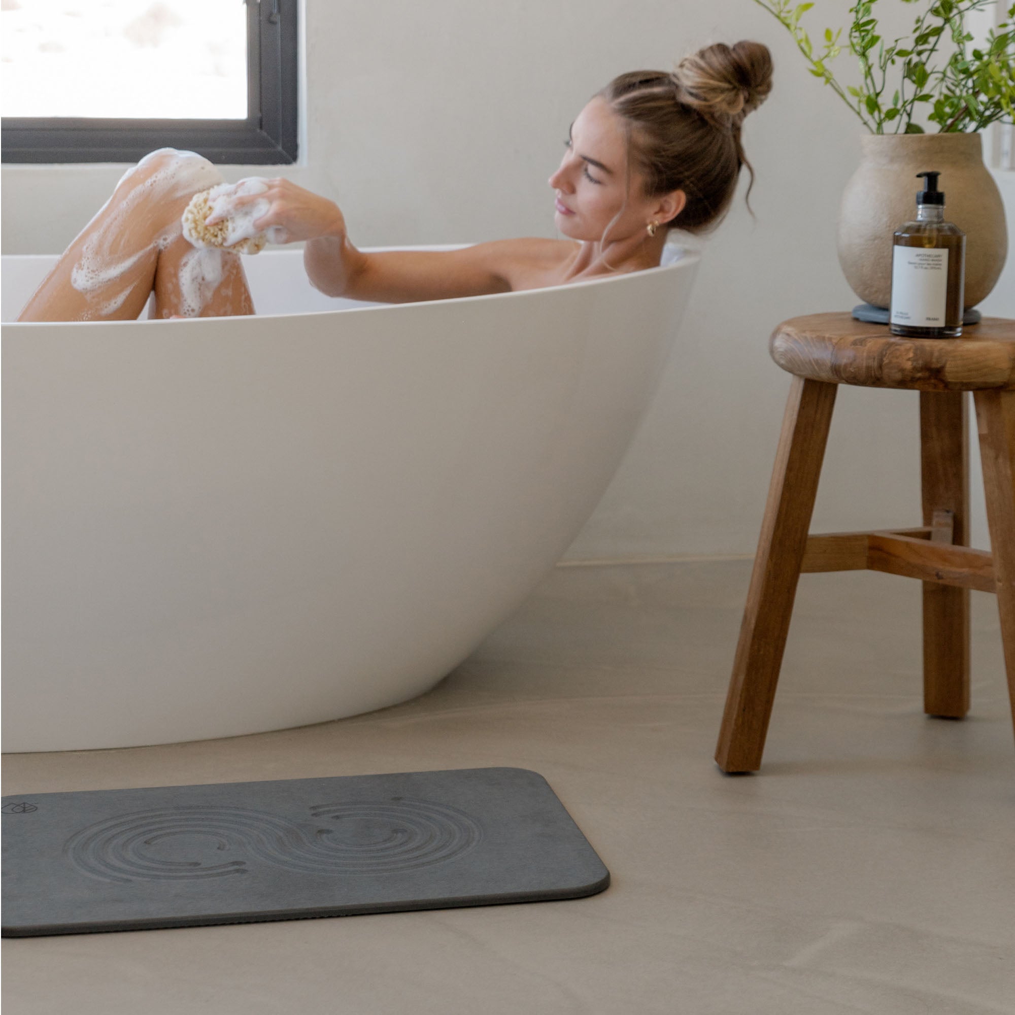 Original bath stone in Slate in front of free-standing tub with woman bathing