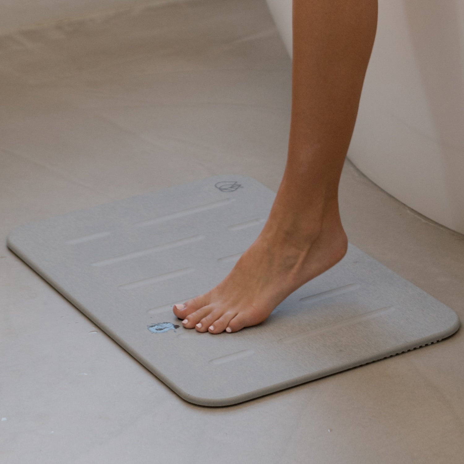 model stepping out of bath tub on stone bath mat