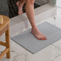 woman stepping out of shower on bath mat