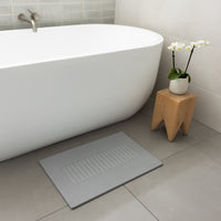 light gray shower mat in front of tub