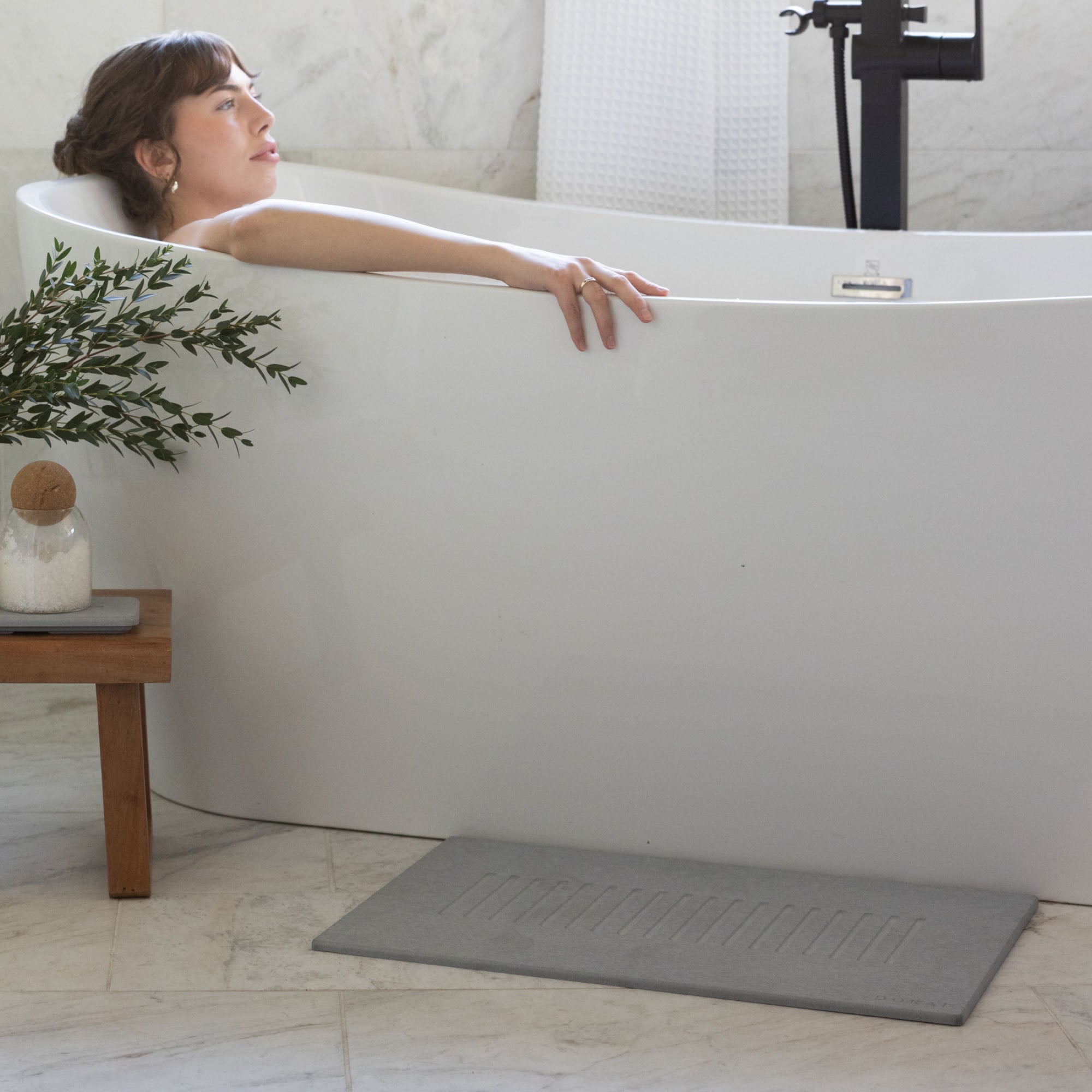 Original bath stone in Ash in front of free-standing tub with woman bathing