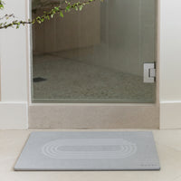 Gray bath mat in front of a glass shower door