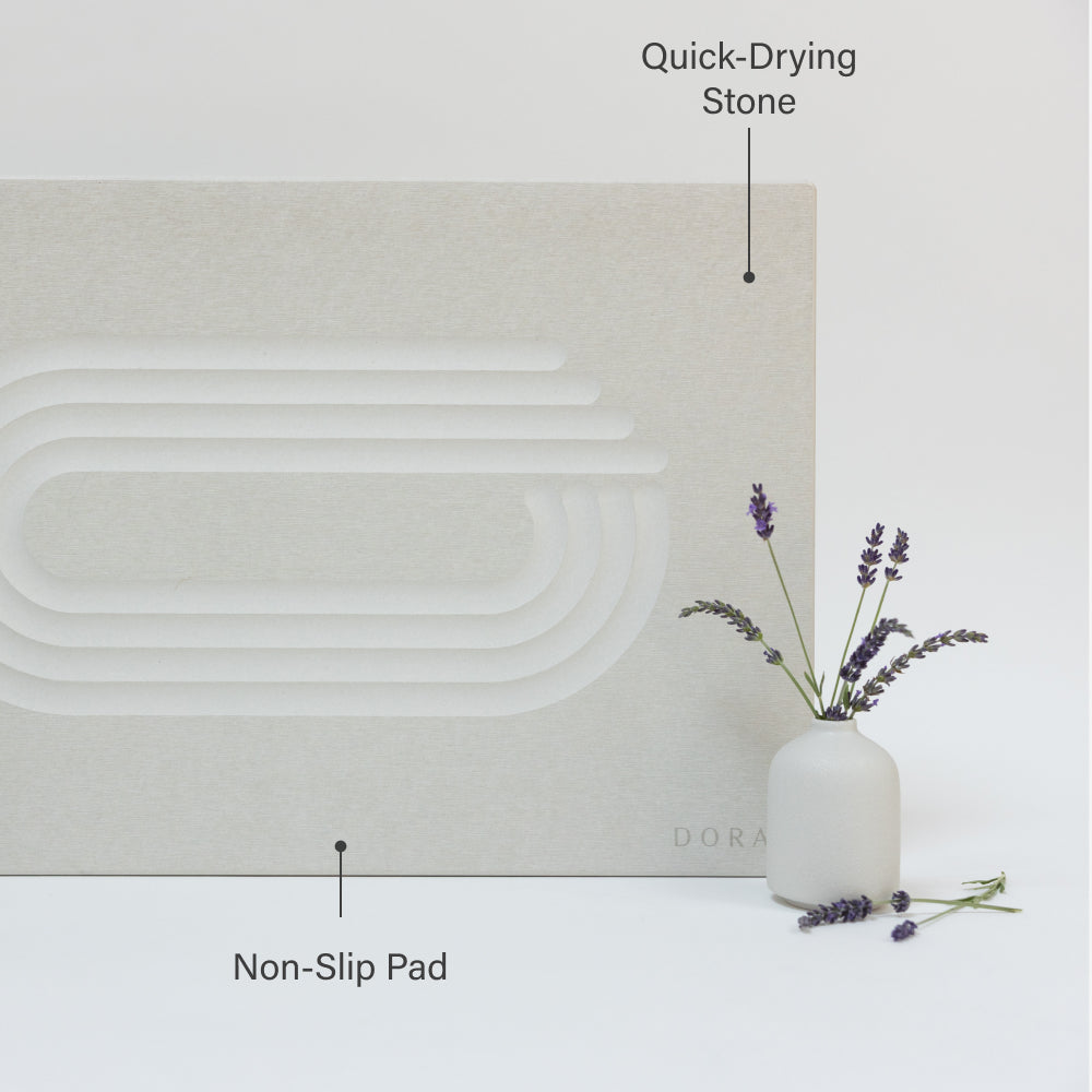 White stone with non-slip pad and quick-drying stone features labeled, next to a white vase with lavender.