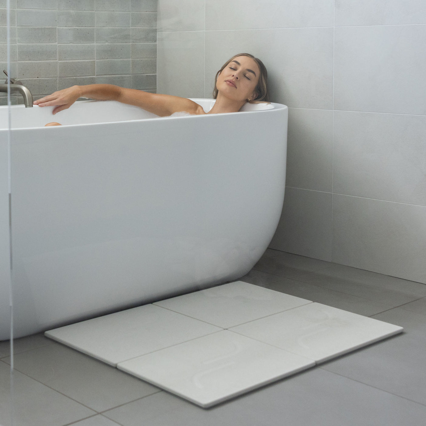 Large arch bath stone mat in Sandstone is quick-drying outside large free-standing tub.