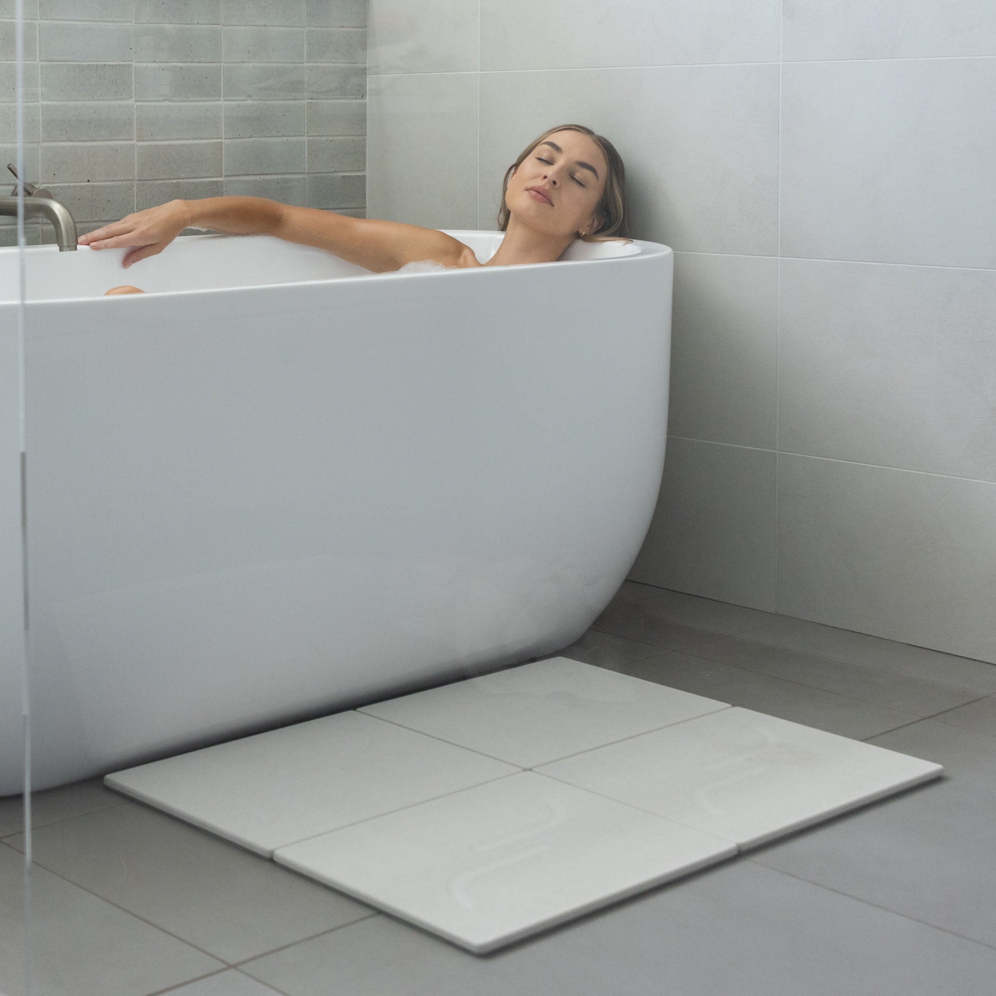 Large arch bath stone mat in Sandstone is quick-drying outside large free-standing tub.