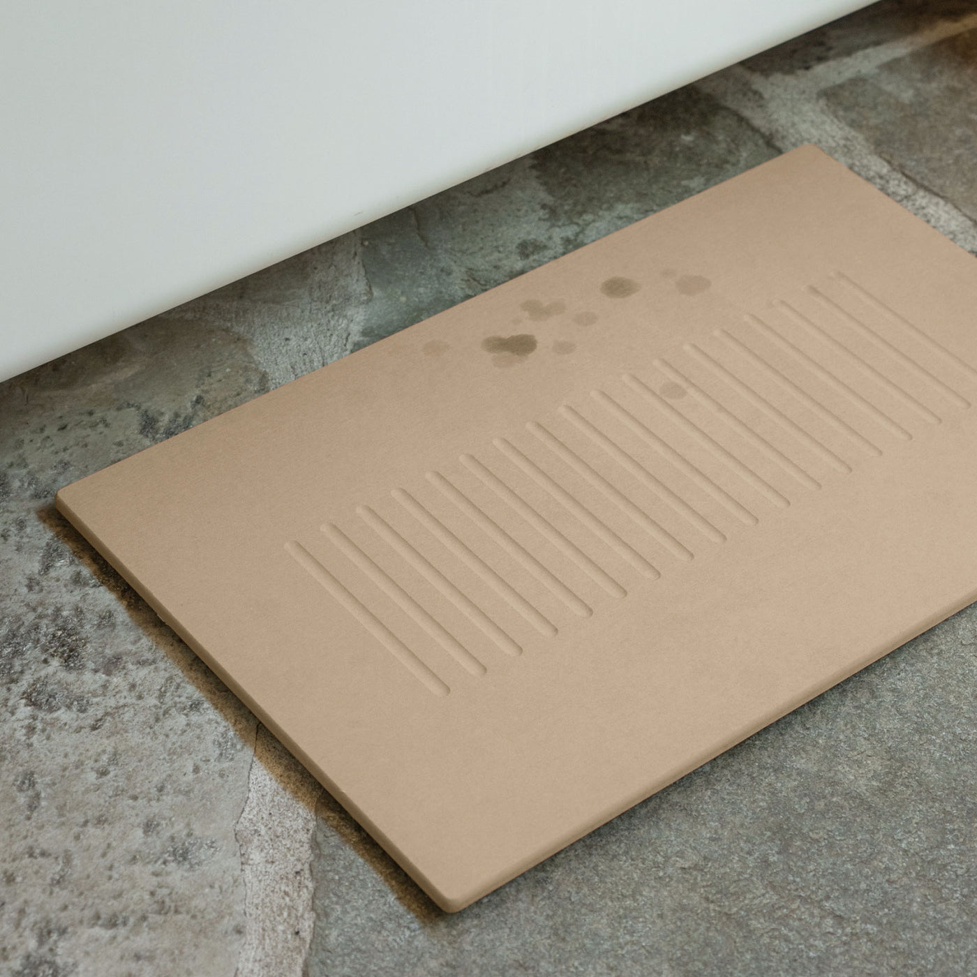 Aspen Clay Bath Stone Mat on stone tile in bathroom.