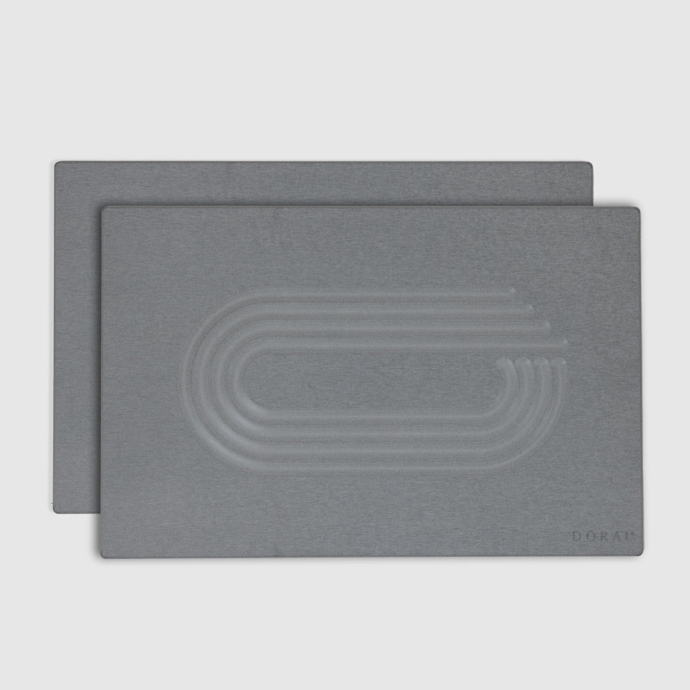 Two gray bath mats with an embossed design on a light gray background