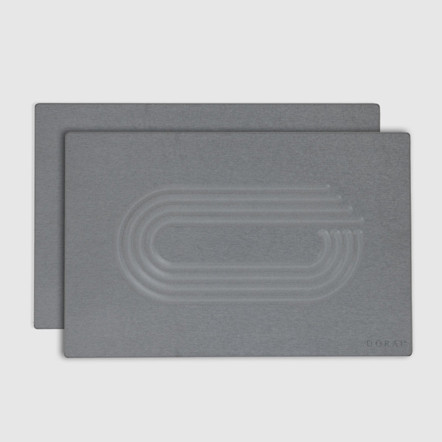Two gray bath mats with an embossed design on a light gray background