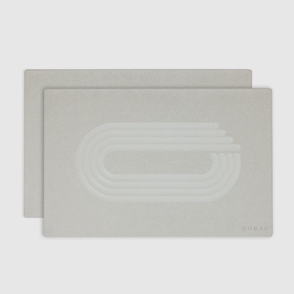 Two of white bath mats with a subtle pattern on a white background