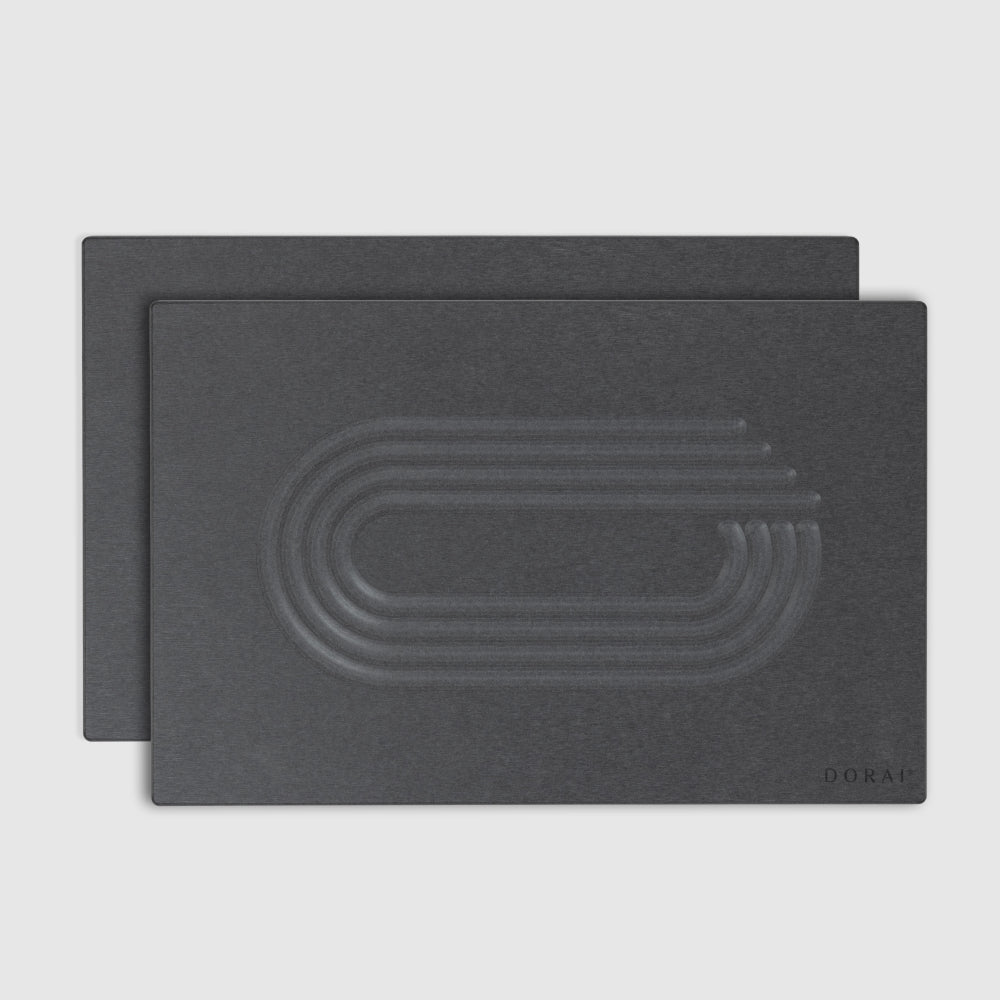 Two dark gray shower mats with embossed design on a light gray background
