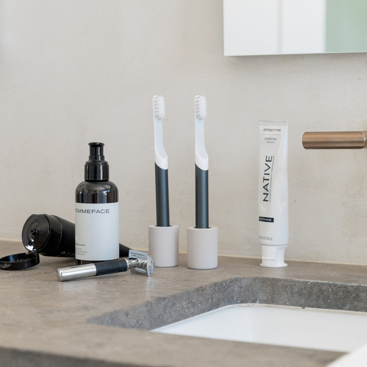 Small, light gray  toothbrush holder set with two narrow electric toothbrushes in bathroom.