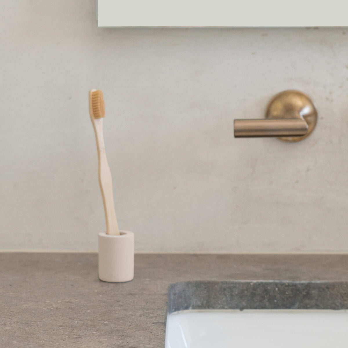 Soft Beige Small Toothbrush Holder in bathroom with standard toothbrush. 