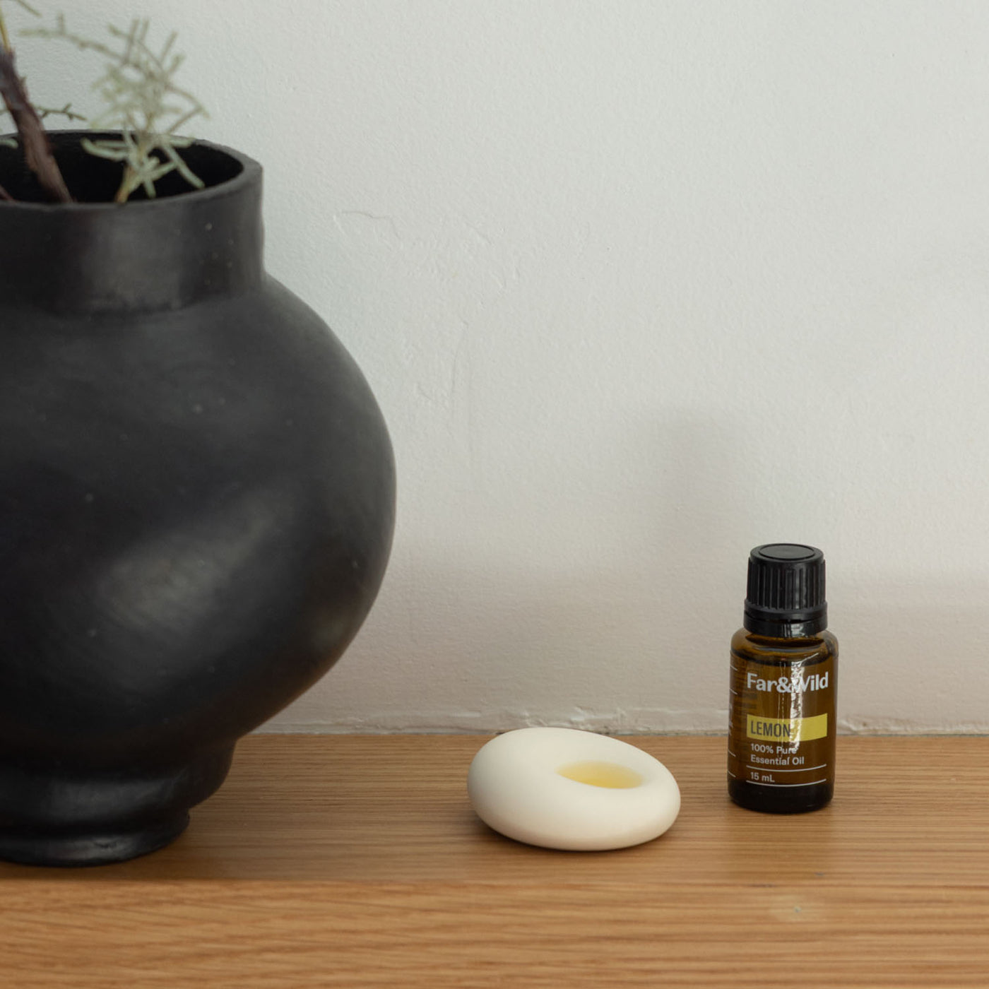 scent stone with essential oil dropper on a shelf next to a vase