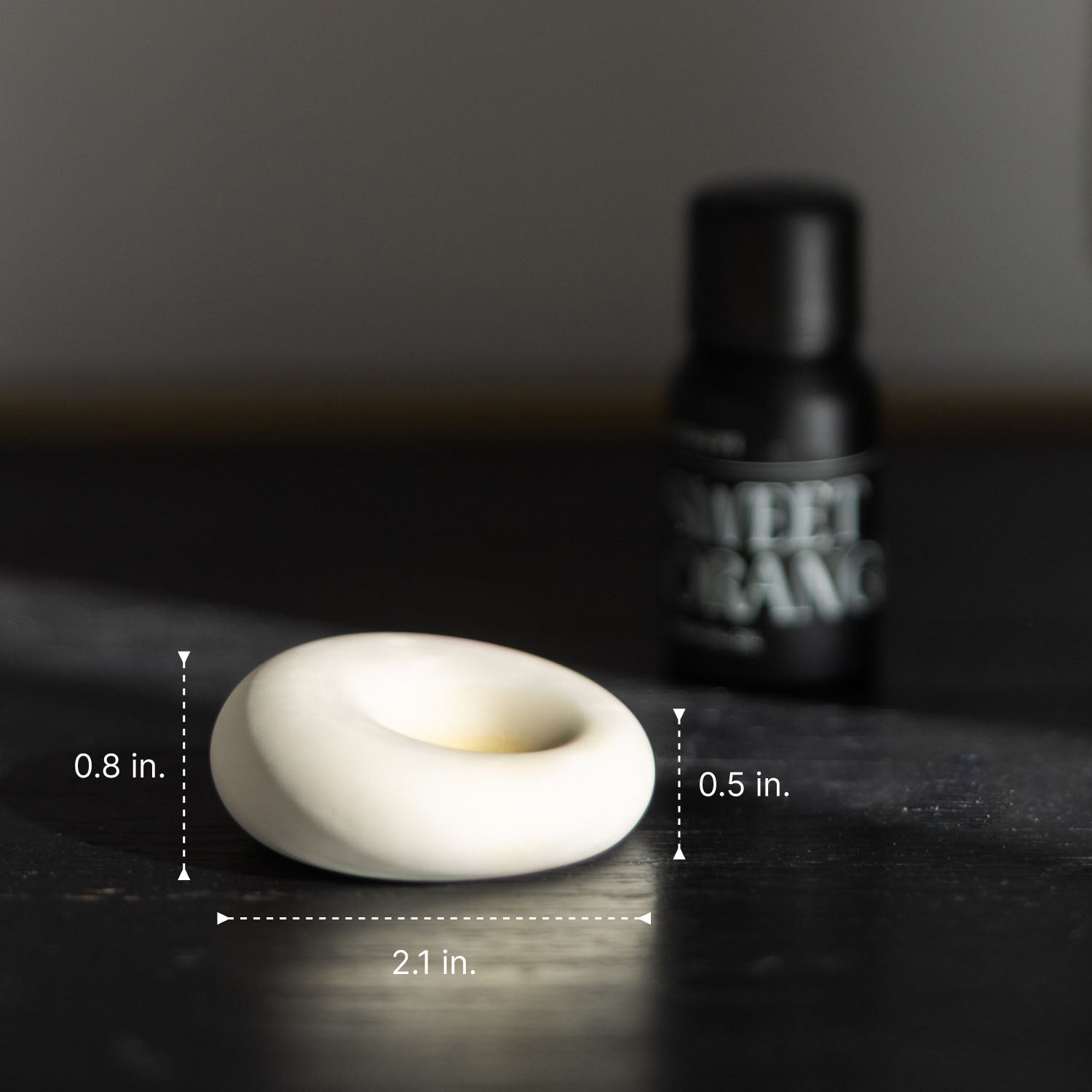 Scent stone stone with measurements on a dark surface, with essential oil dropper in the background.