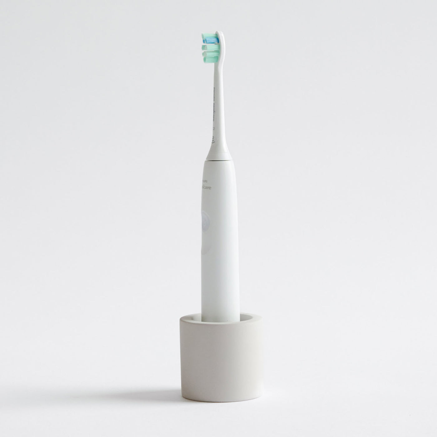 Electric toothbrush in a Soft Beige, stone toothbrush holder on a light gray background