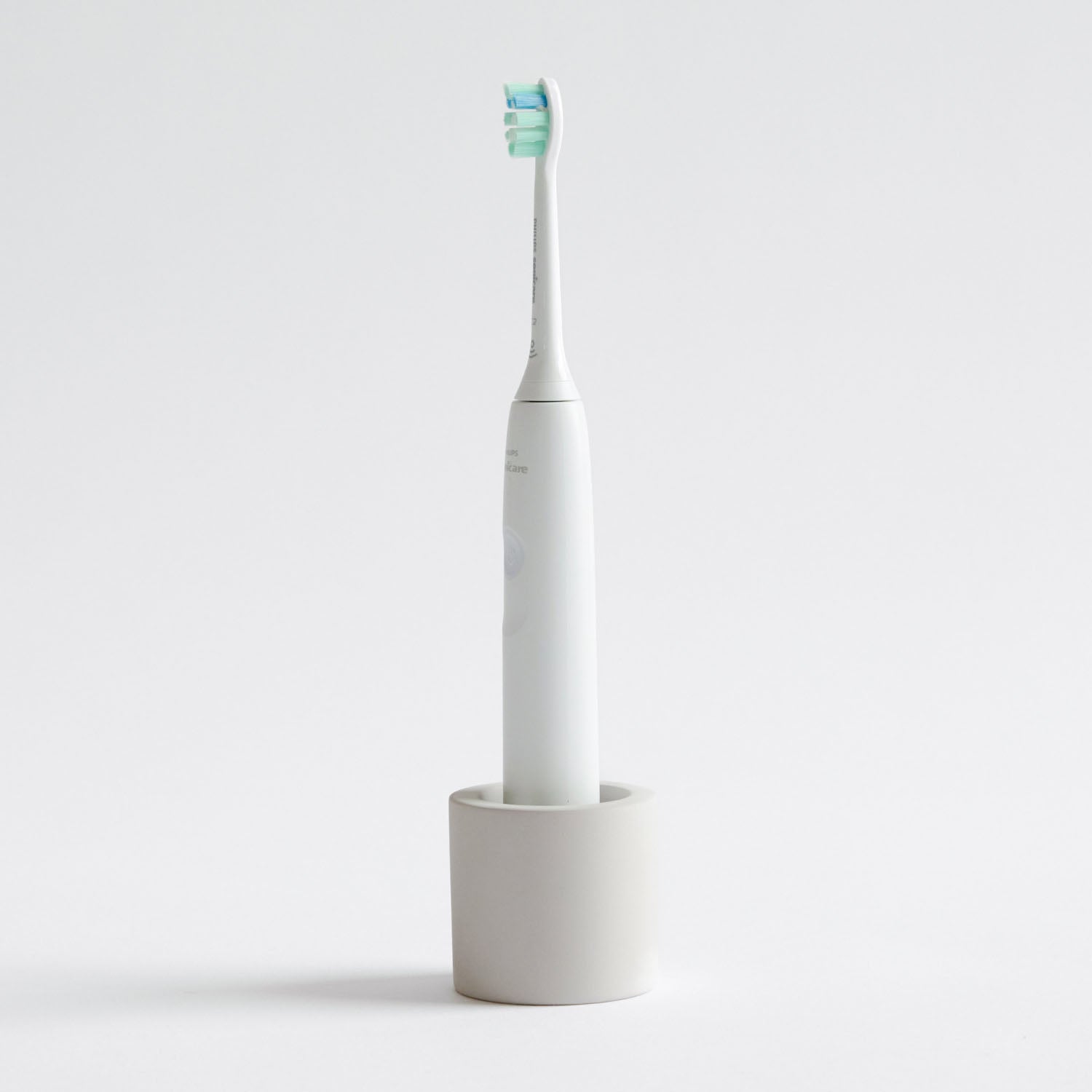 Electric toothbrush in a Soft Beige, stone toothbrush holder on a light gray background