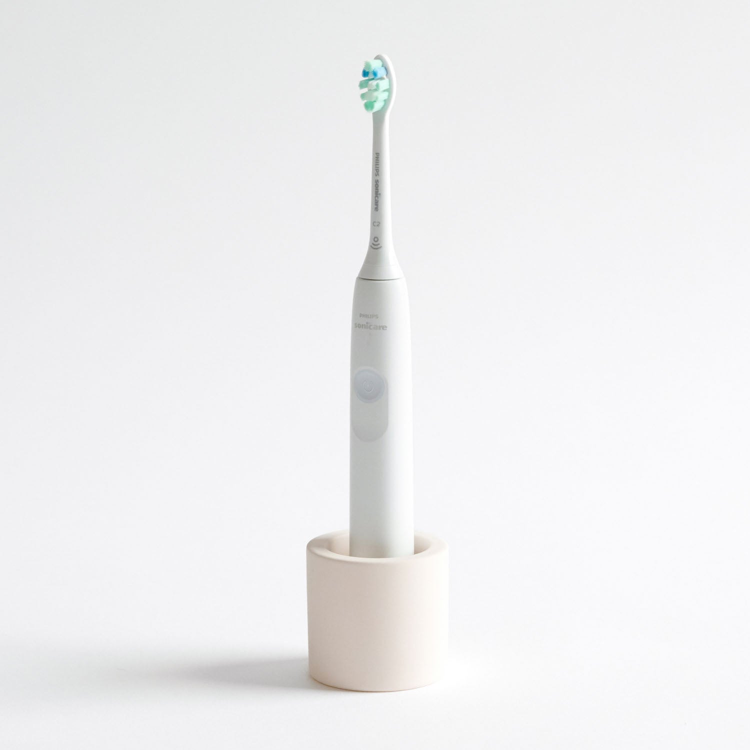 Electric toothbrush in a Soft Beige, stone toothbrush holder on a light gray background