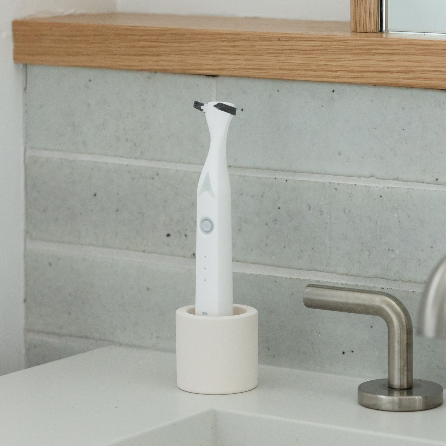 Electric flosser in a stone toothbrush holder on a counter next to a bathroom sink.