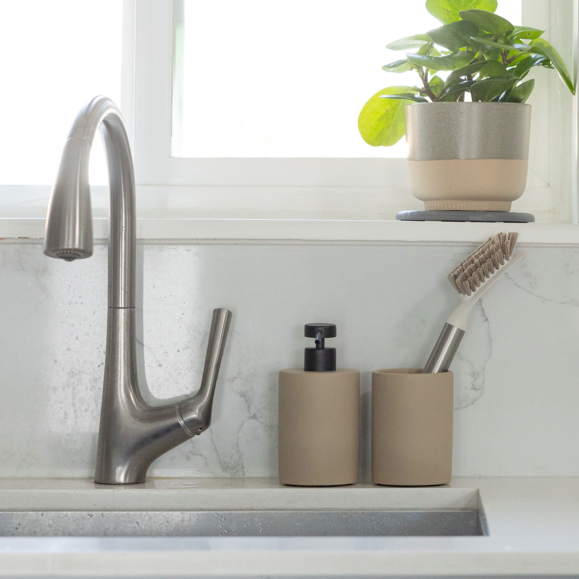Taupe sink holder and brush set in modern kitchen.