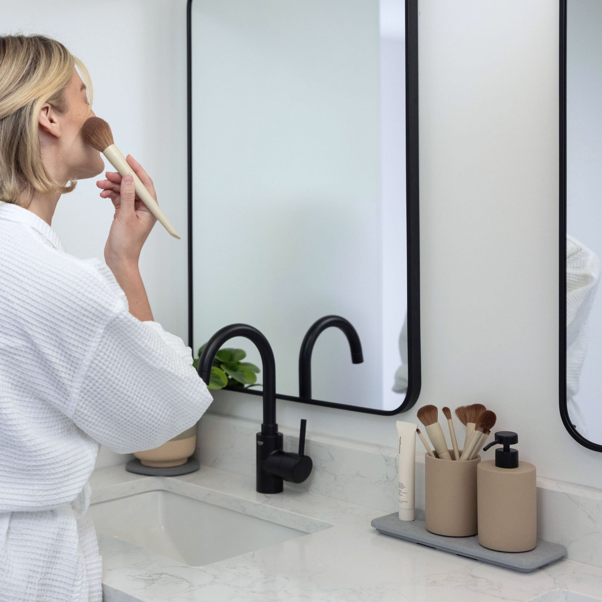 Taupe brush holder and soap dispenser in modern bathroom.