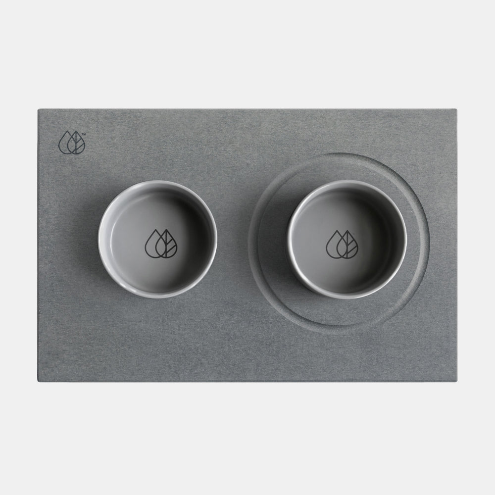 Two gray bowls with a leaf logo on a matching gray mat.