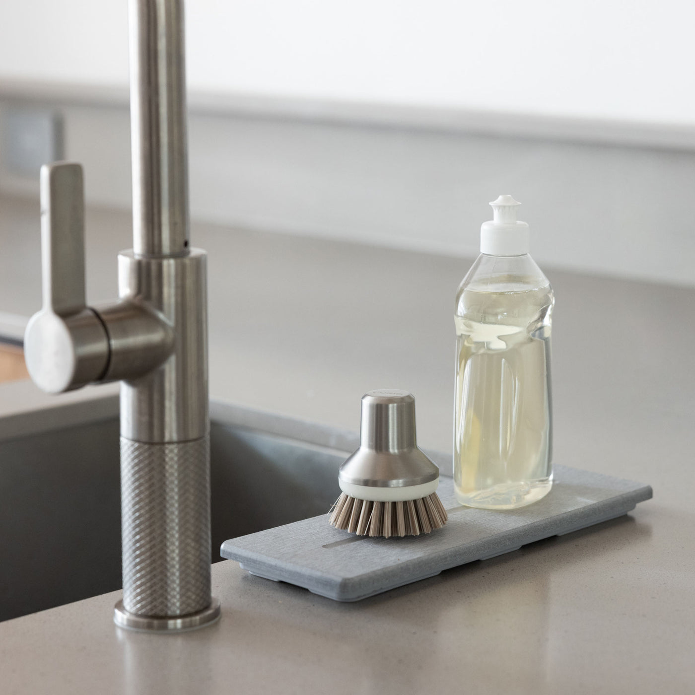 Stone Sink Caddy in Ash with dish soap and scrub brush prevents pooling water around kitchens sink. 
