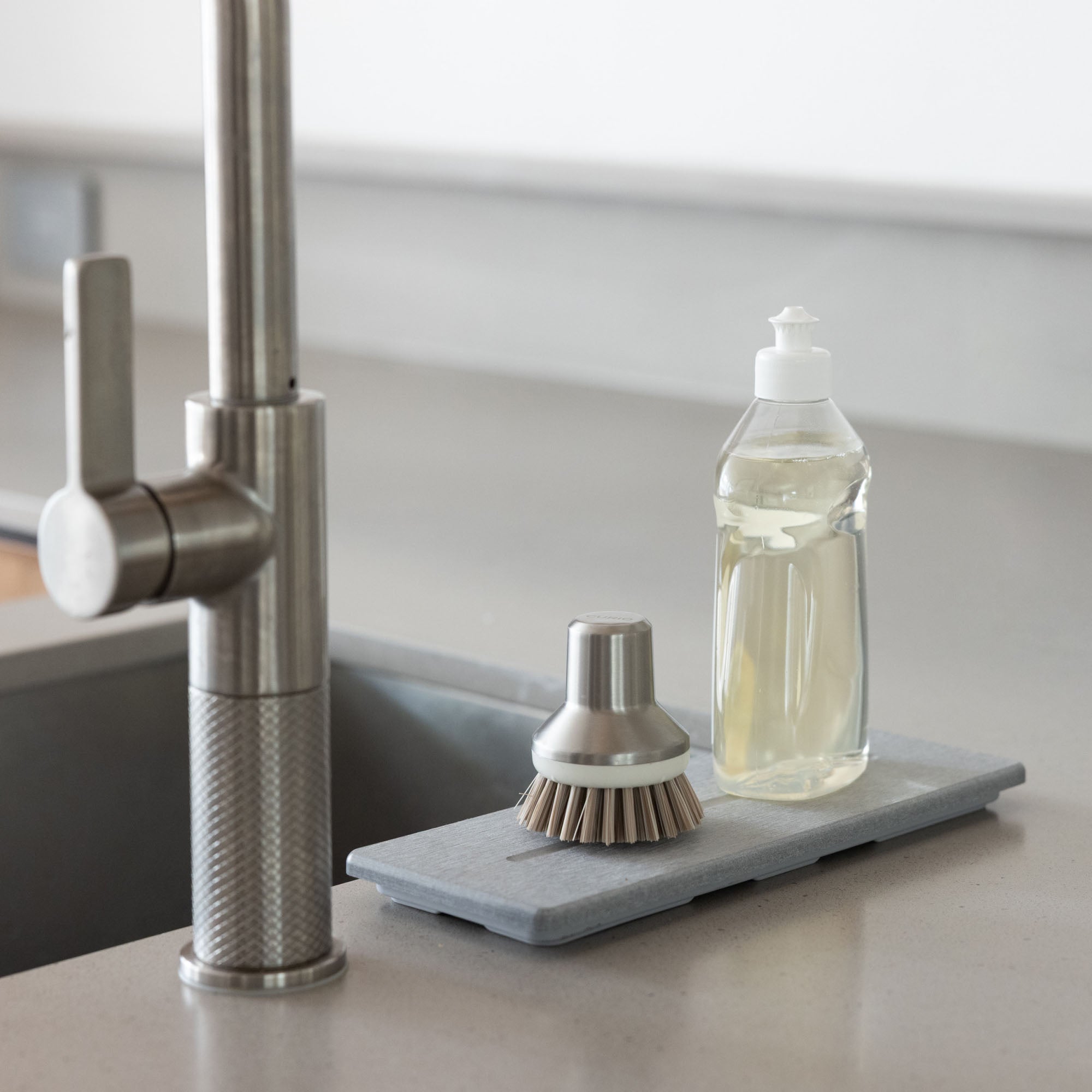 Stone Sink Caddy in Ash with dish soap and scrub brush prevents pooling water around kitchens sink. 