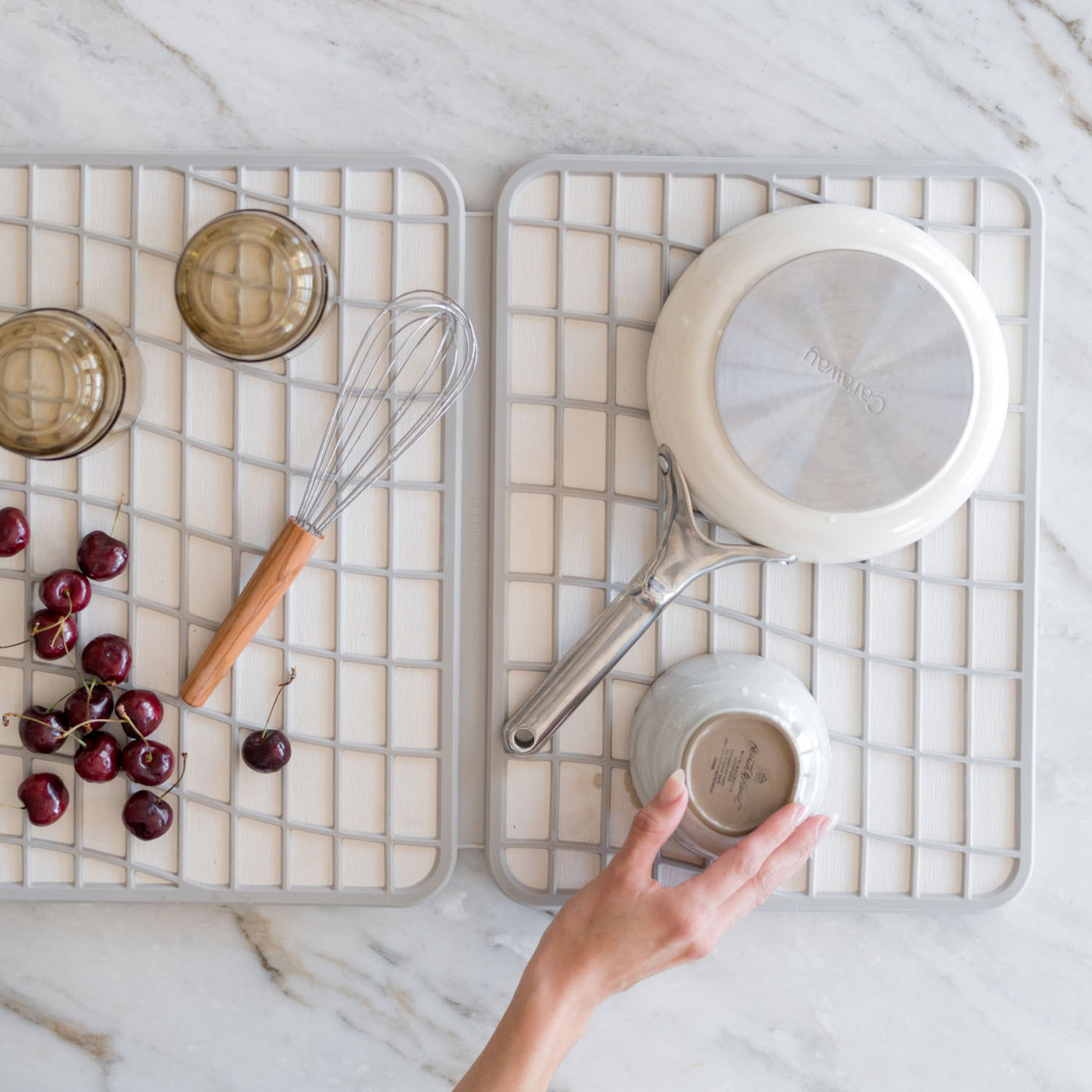 Kitchen utensils including a whisk, ladle, and cherries drying on stone on a marble surface