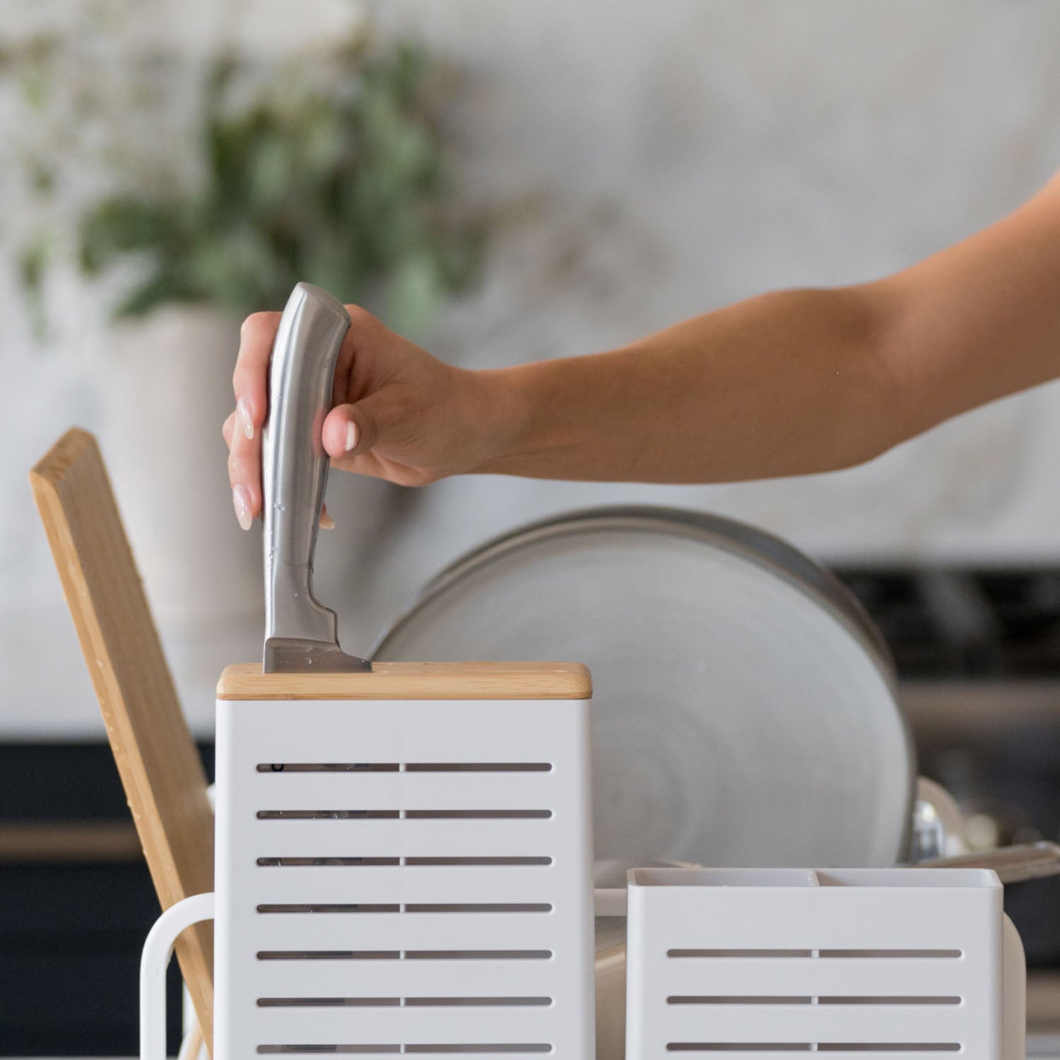 kitchen knife being inserted into wooden topper of dish rack