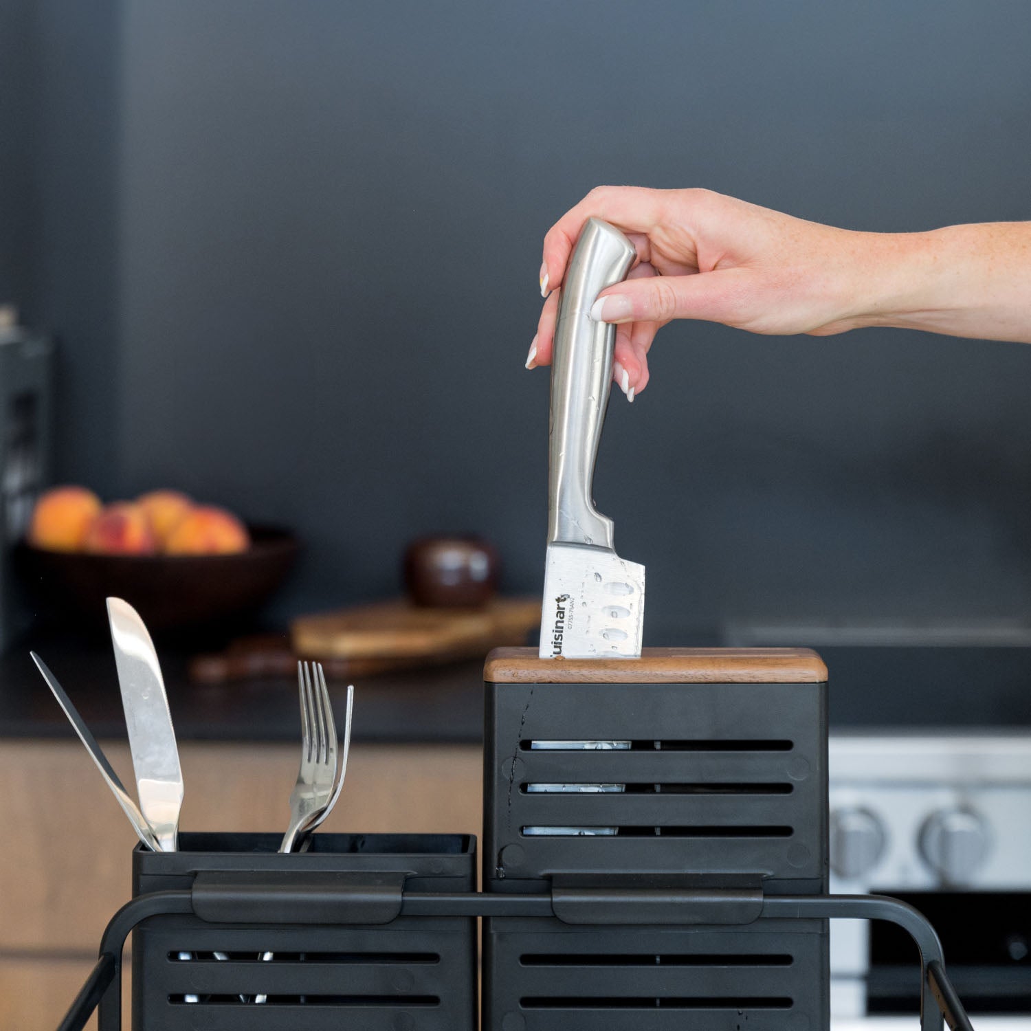 Person holding a knife over a knife block with a kitchen background