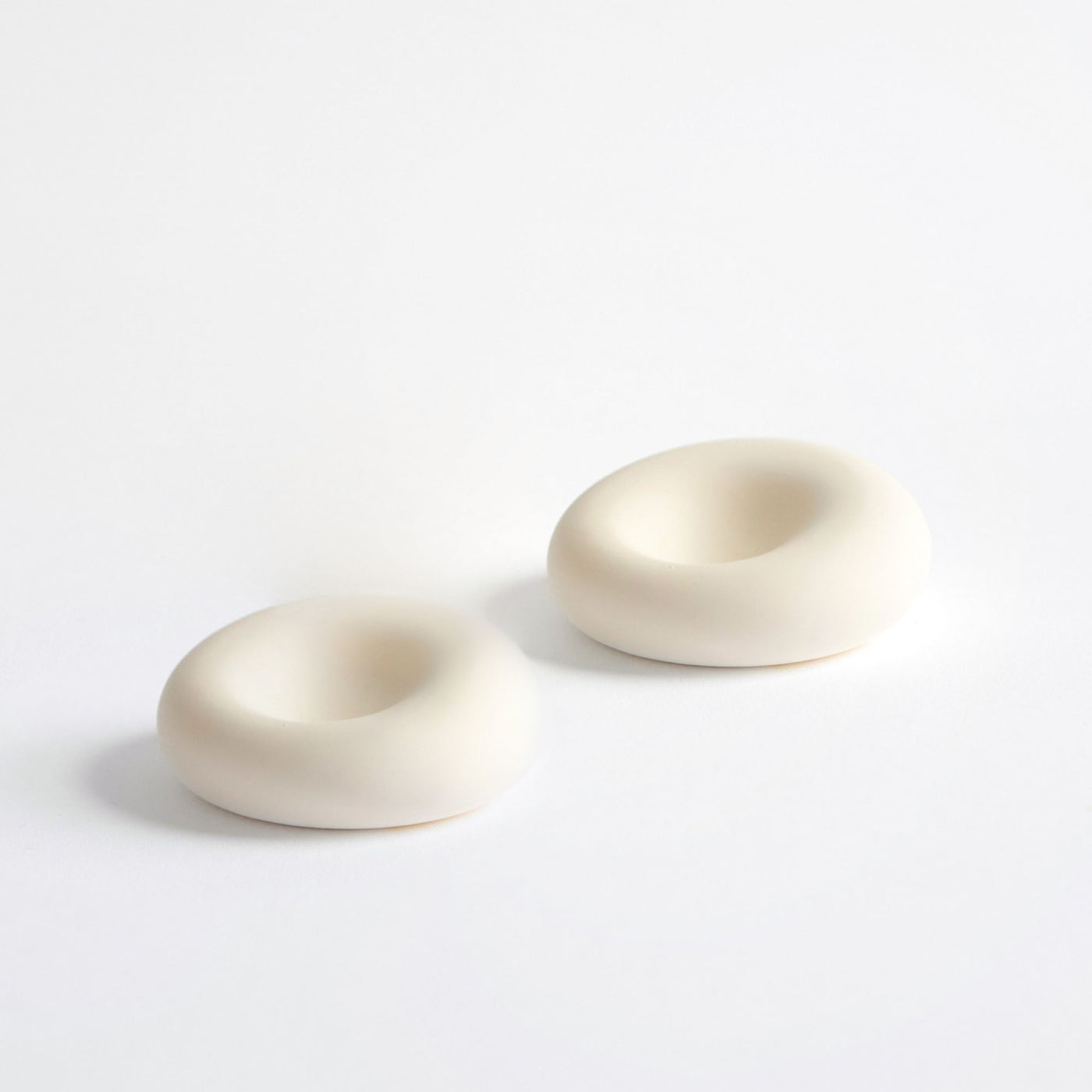 Two beige ceramic donut-shaped objects on a white background