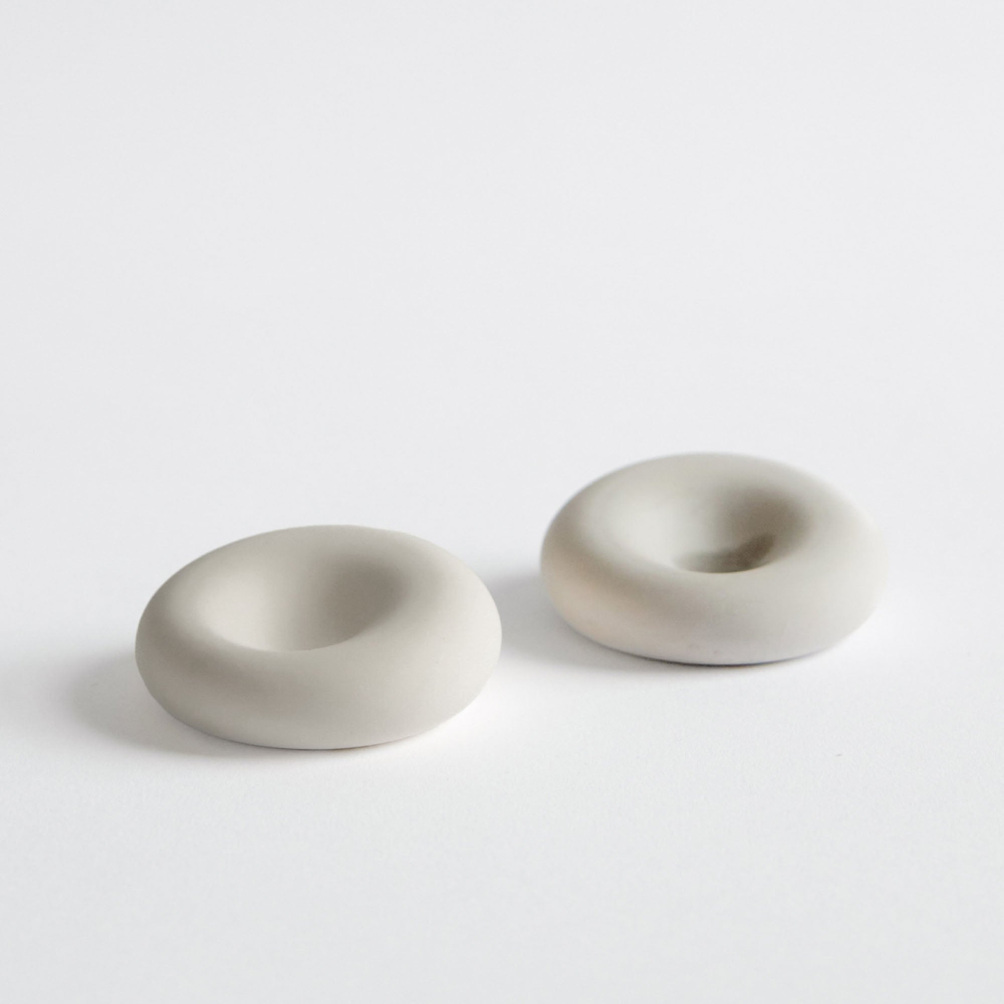 Two light grey scent donut-shaped stones on a white background