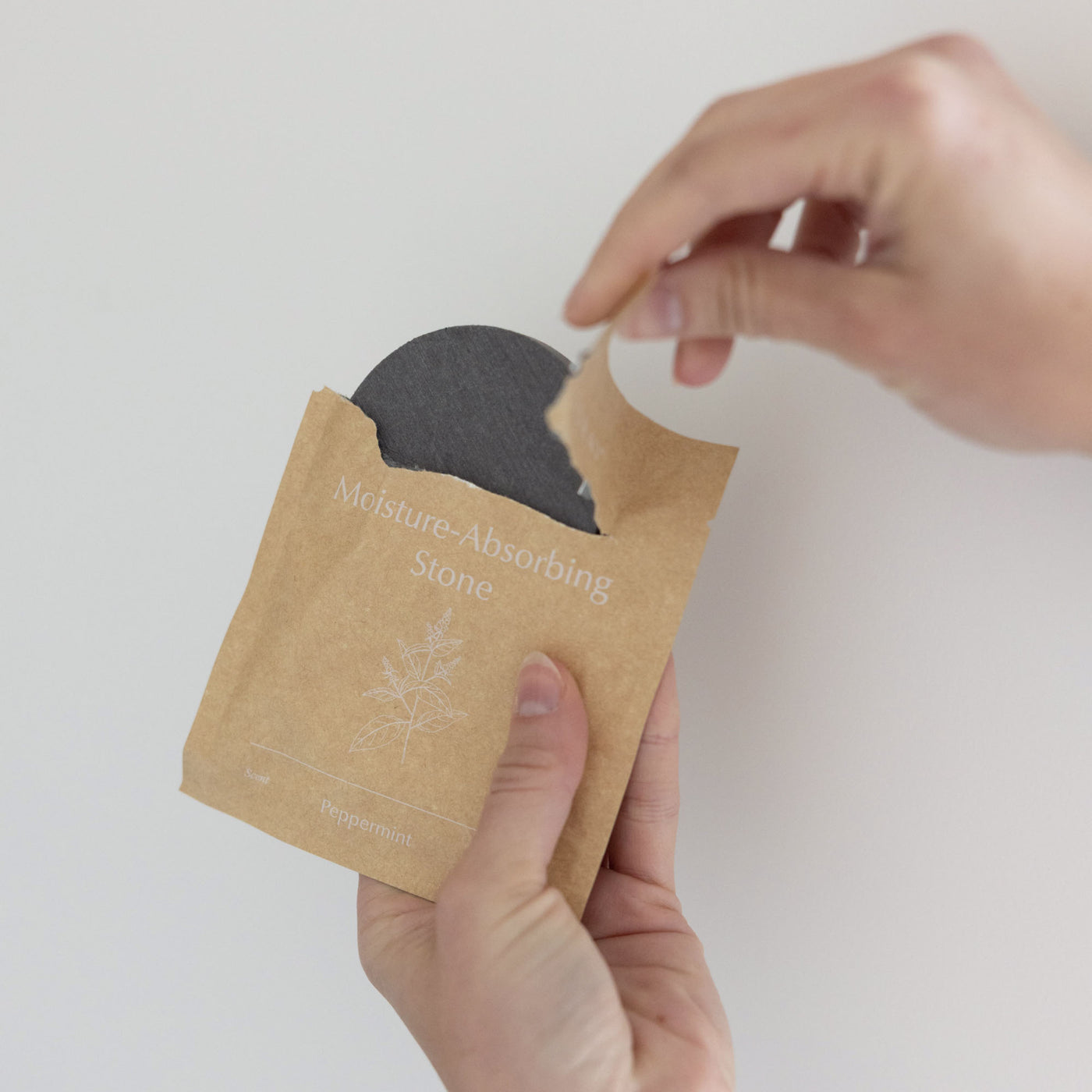 Person opening moisture-absorbing stone for peppermint toilet brush cleaner. 