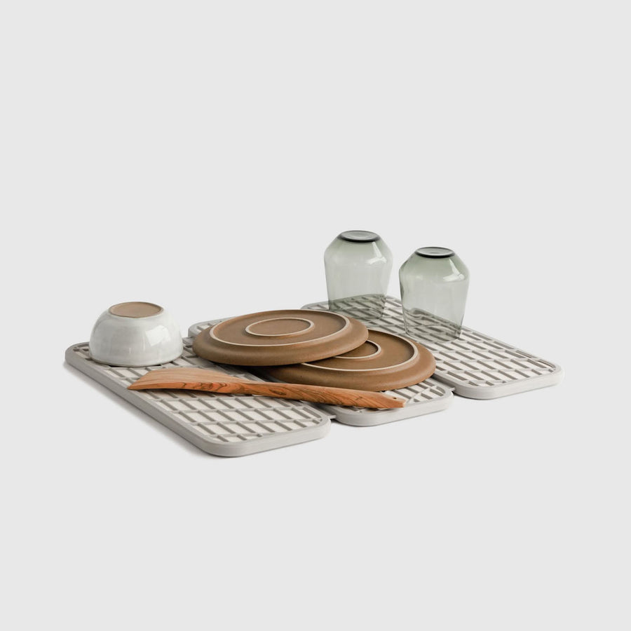 Drift Sandstone Dish Pad with plates and glasses on white background.