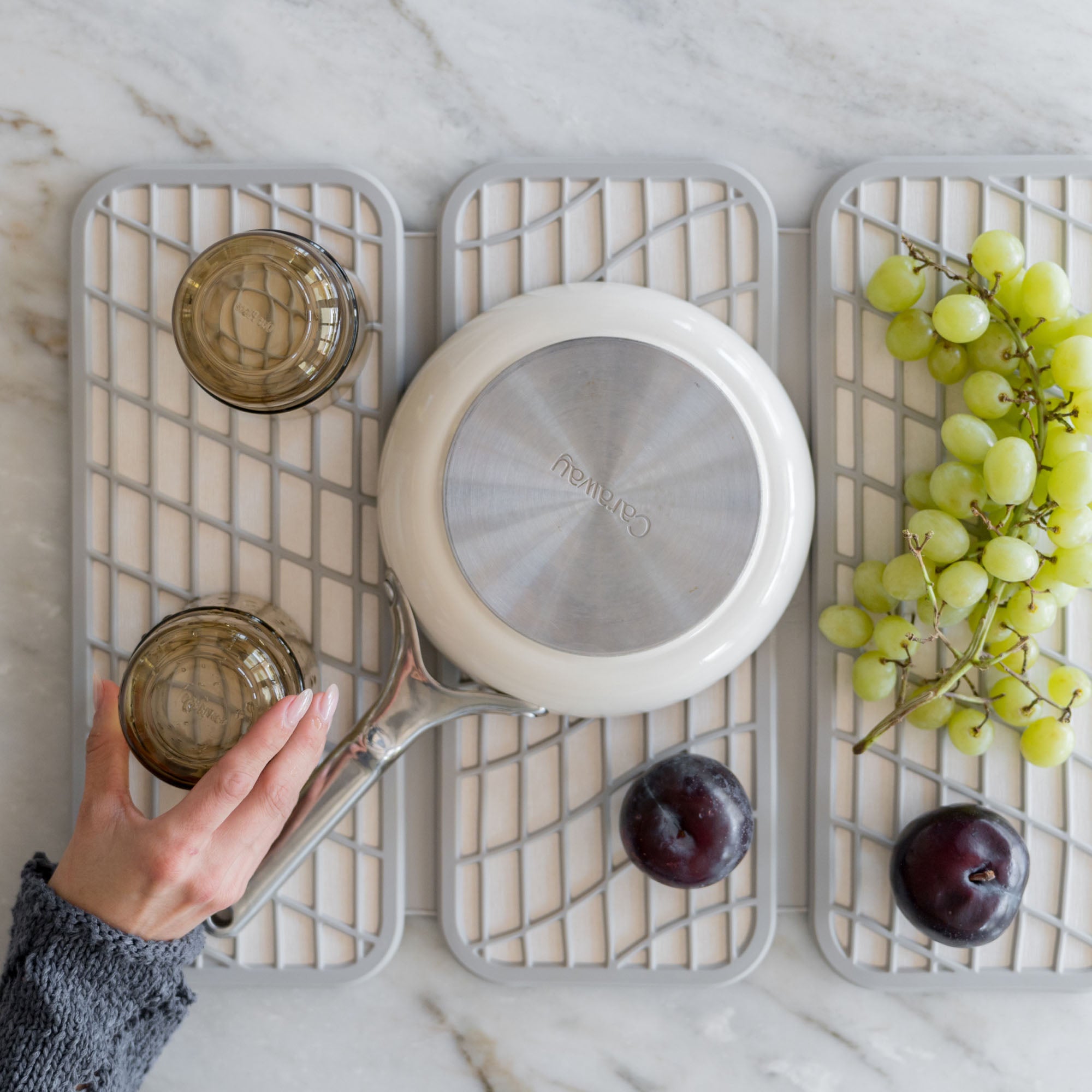 Drift Sandstone Dish Pad with produce, pots, and glasses.