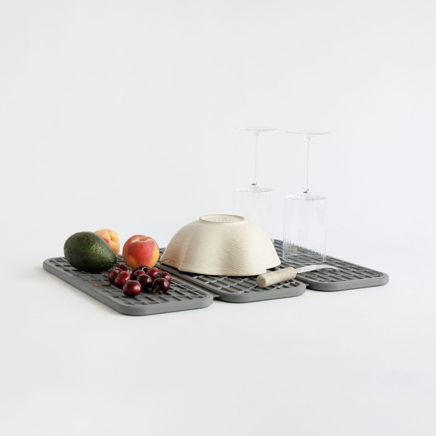 Drift Slate Dish Pad with cooking utensils and produce on white background.
