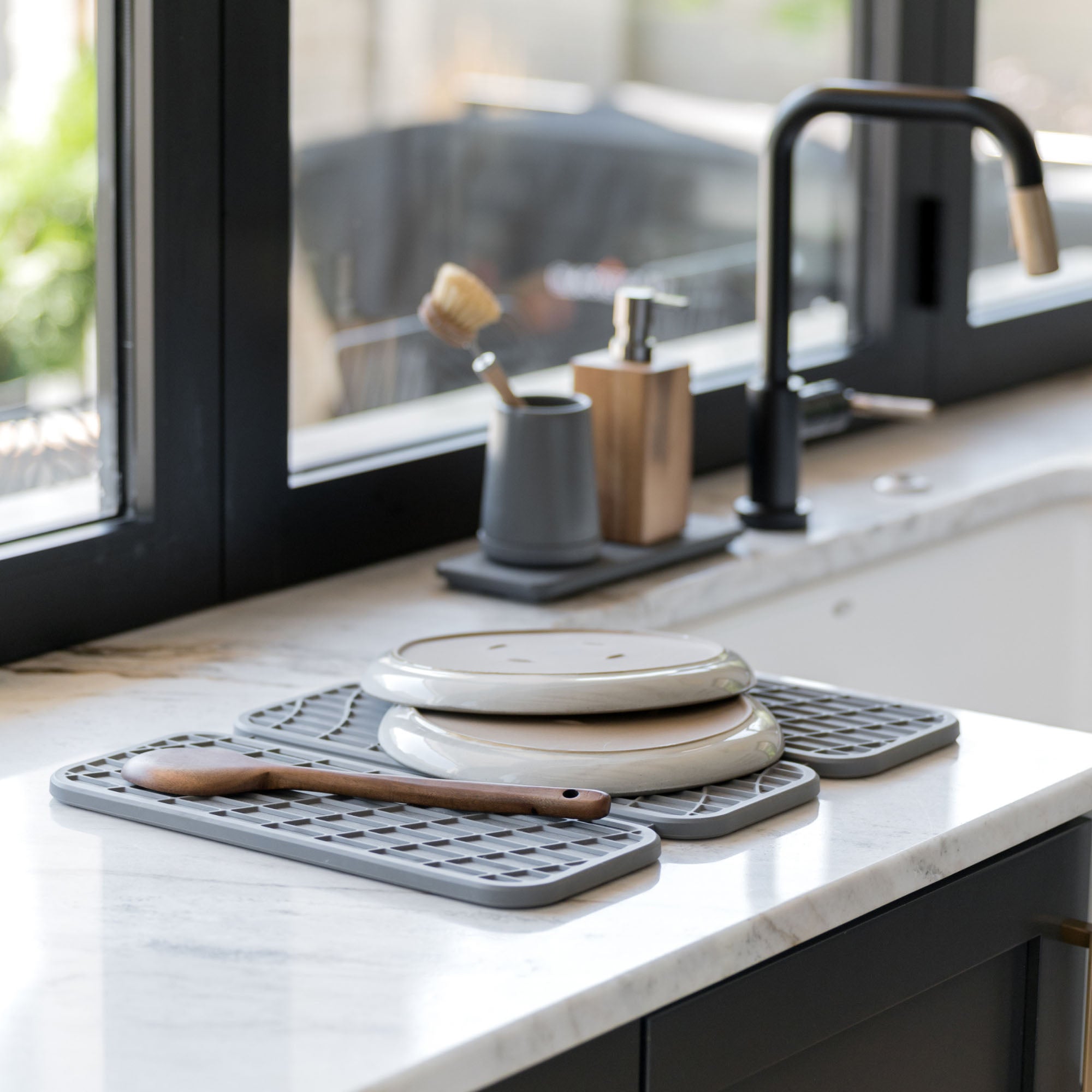Woman with Drift Slate Dish Pad with plates and utensils on it in beautiful kitchen.