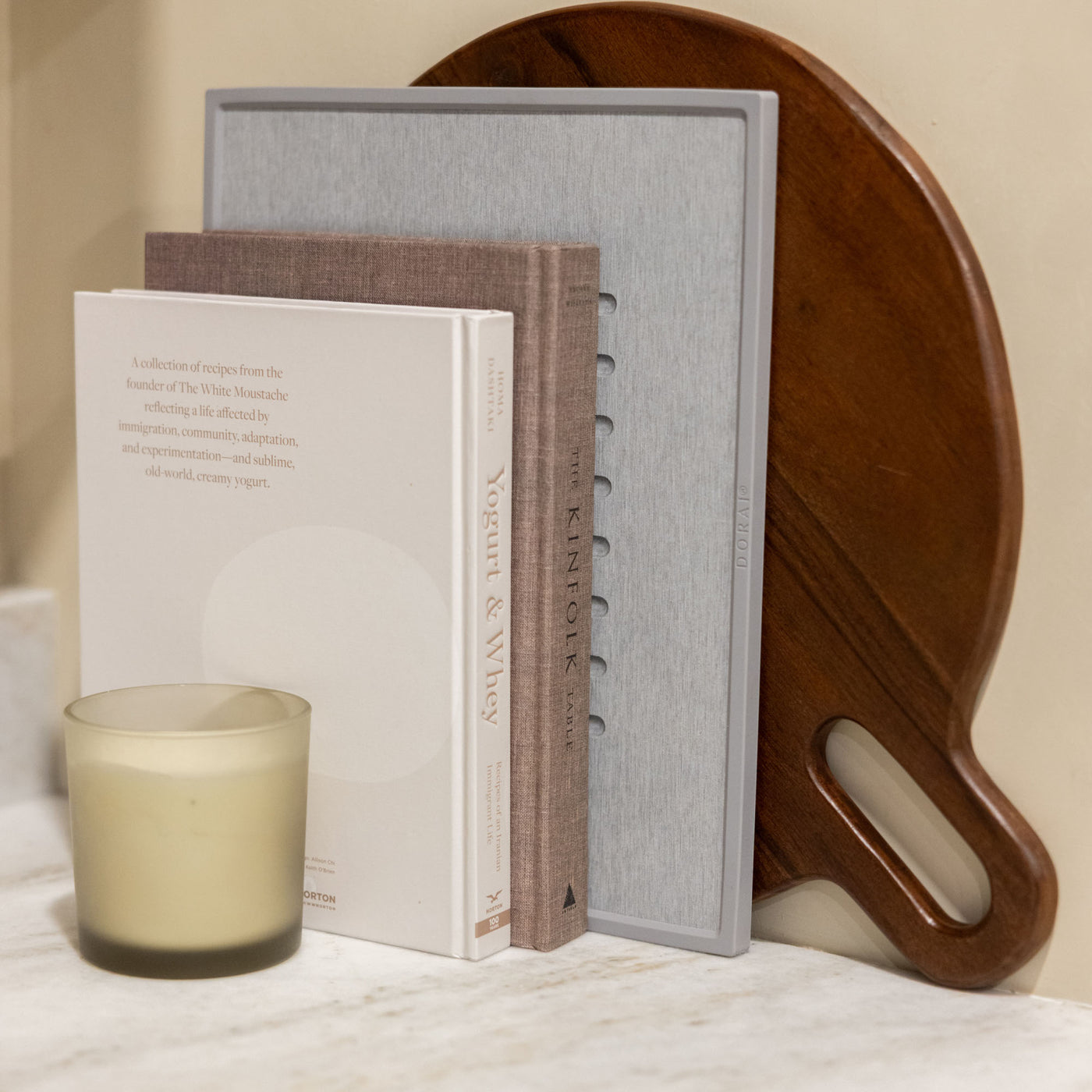 Beautiful ash dish mat with modern, wood cutting board and cookbooks for minimalist kitchen.